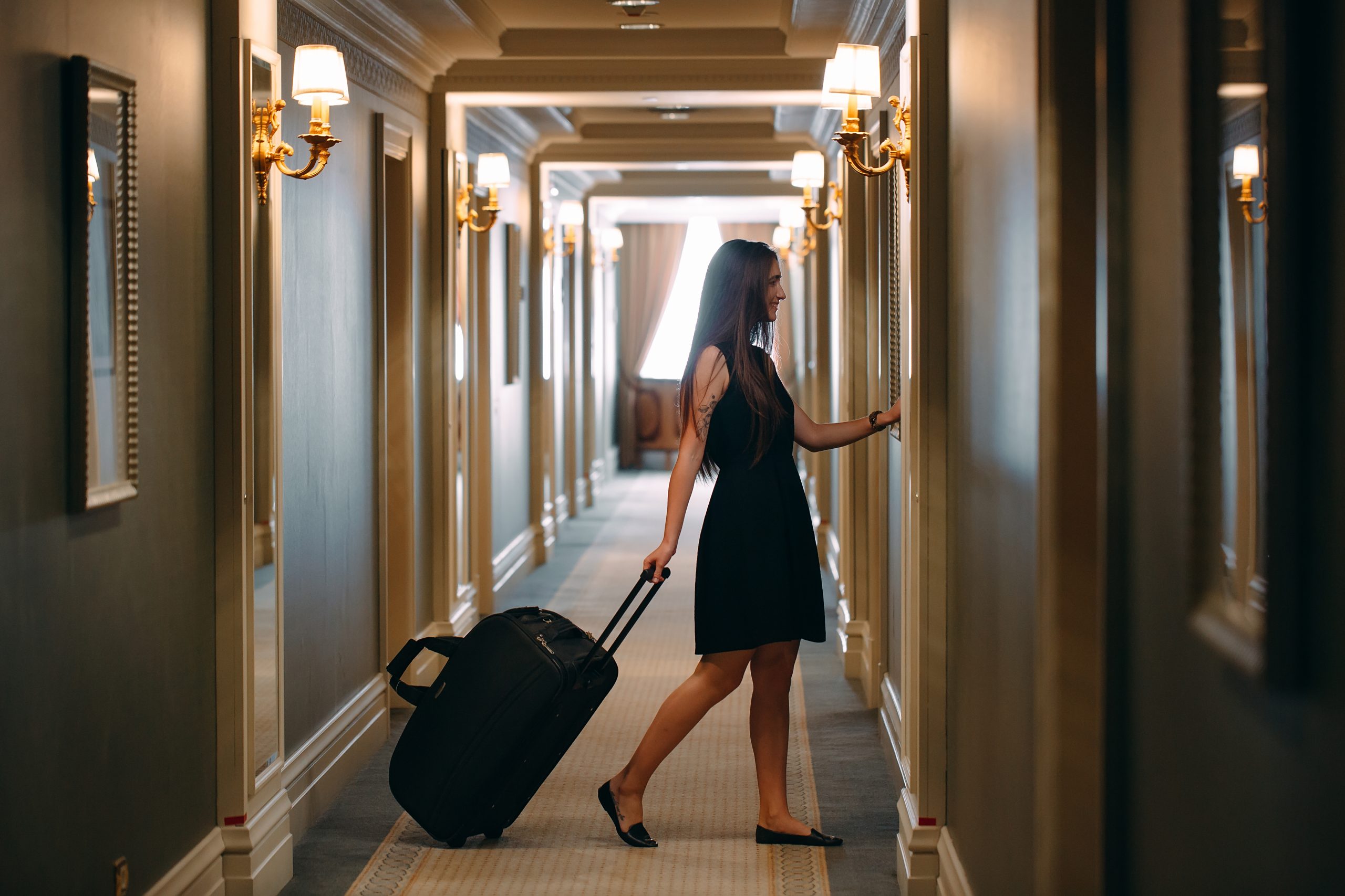 Young woman with handbag and suitcase in an elegant suit walks t